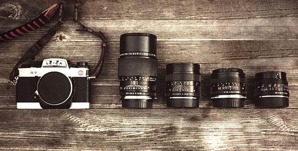 Alte Spiegelreflexkamera mit verschiedenen Objektiven auf einer Holzoberfläche, Vintage-Fotografieausrüstung.