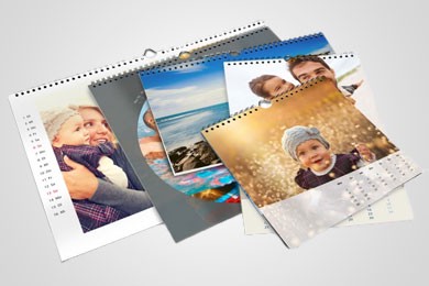 Fotokalender mit persönlichen Bildern, darunter Familienporträts und Meereslandschaft, auf hellgrauem Hintergrund.