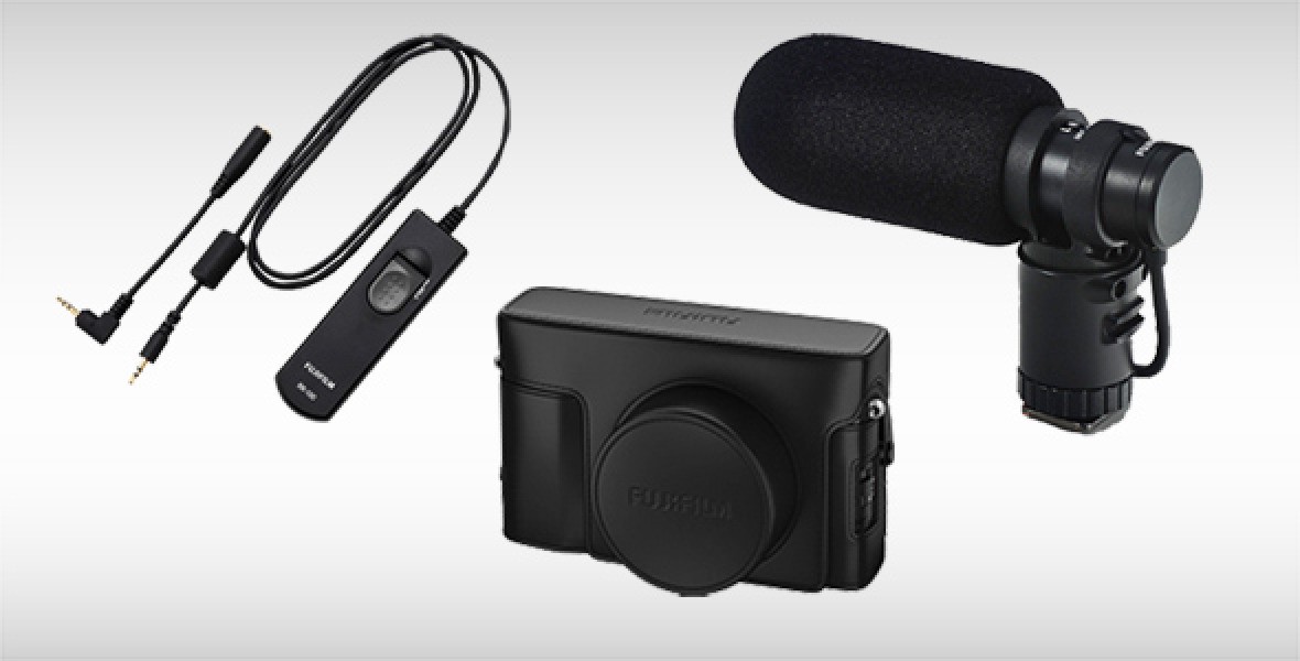 Kompakte Kamera, externes Mikrofon und kabelgebundener Fernauslöser auf grauem Hintergrund.